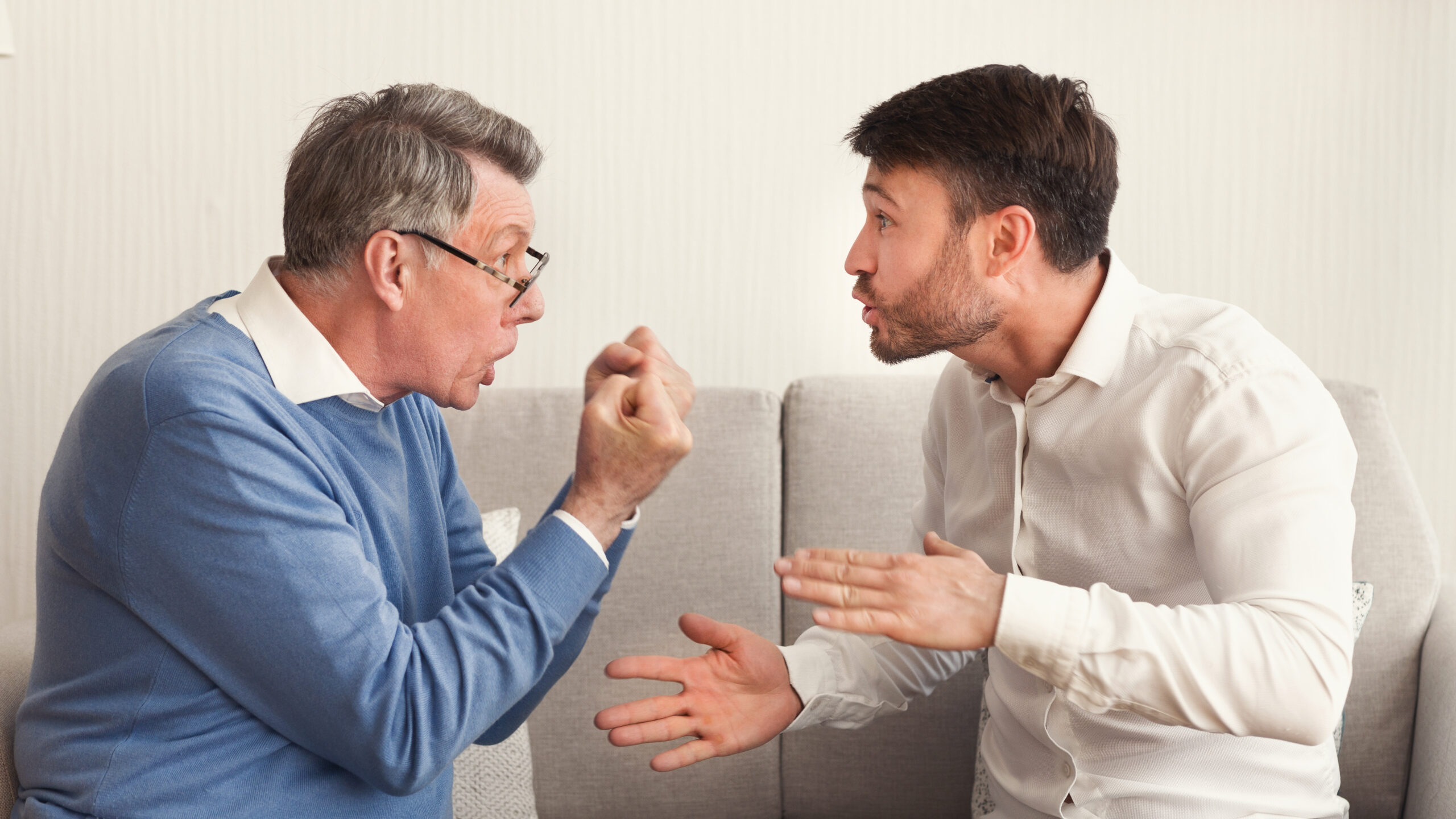 One older white man and younger white man with angry facial expressions and hand gestures in an argument.